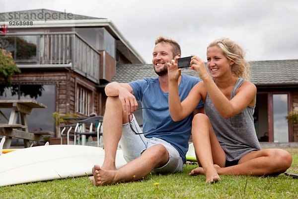 Junges Surferpaar fotografiert mit Smartphone