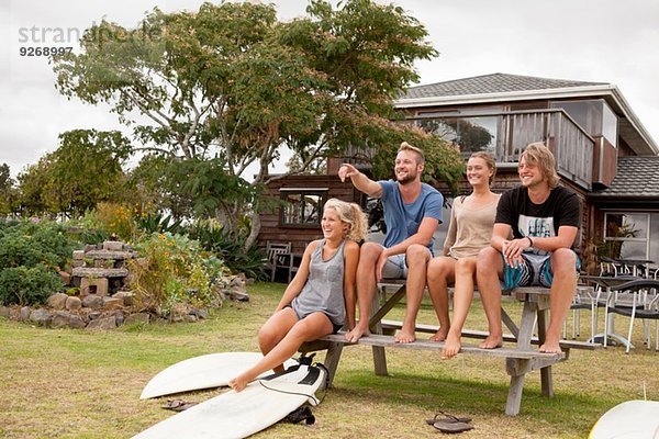 Vier Surferfreunde sitzen auf der Picknickbank