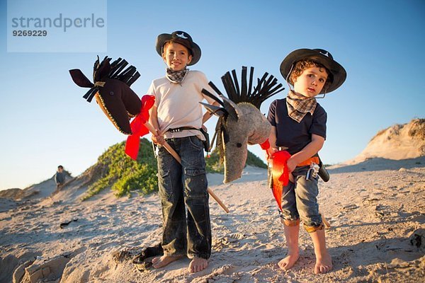 Zwei Brüder verkleidet als Cowboys mit Hobbypferden.