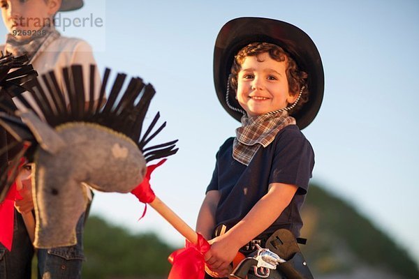 Zwei Brüder verkleidet als Cowboys auf Hobbypferden