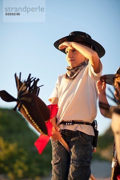 Zwei als Cowboys gekleidete Jungen auf Hobbypferden