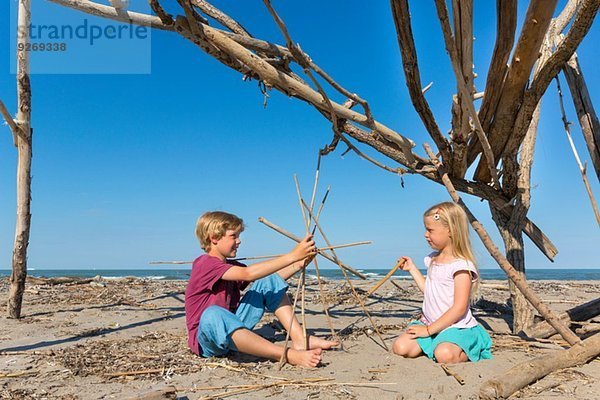 Junge und seine Schwester beim Bau einer runden Struktur aus Treibholz  Caleri Beach  Veneto  Italien