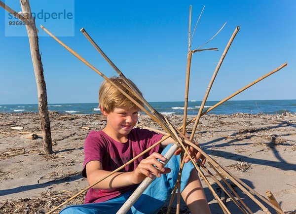 Junge beim Bau einer runden Struktur aus Treibholz  Caleri Beach  Veneto  Italien