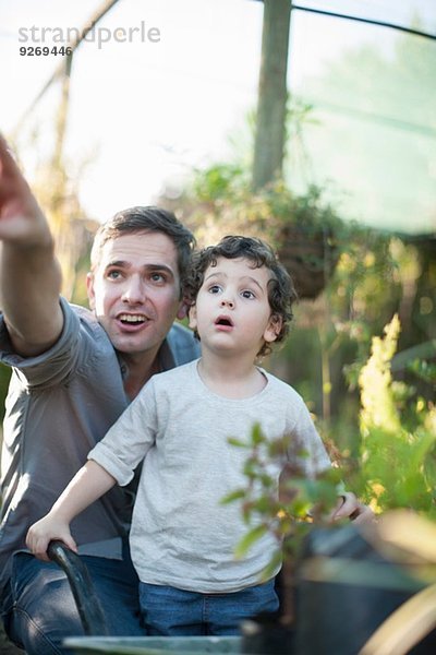 Mittlerer Erwachsener Mann und Sohn  der im Garten überrascht aussieht.