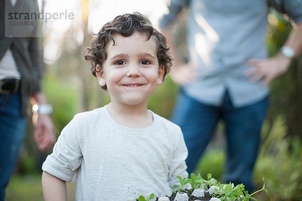Portrait des Jungen mit Pflanzen im Eierkarton im Kleingarten