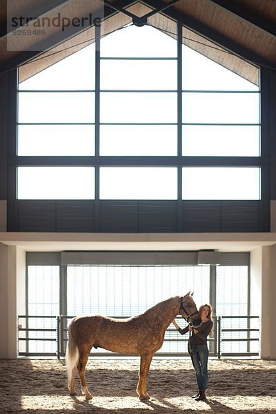 Junge Stallfrau stehend mit Palomino-Pferd