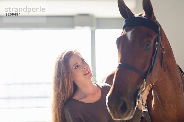 Weibliche Stallhand mit Kastanienpferd im Stall