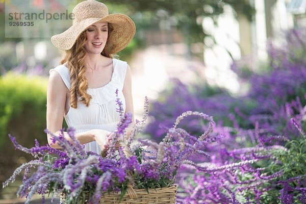 Schöne junge Frau im Garten mit Blick auf lila Blumen