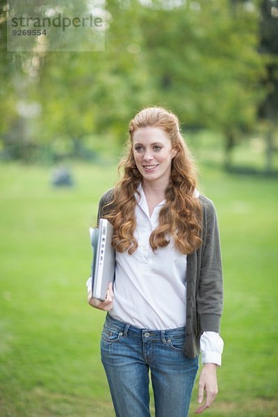 Junge Frau mit Laptop und Spaziergang im Park