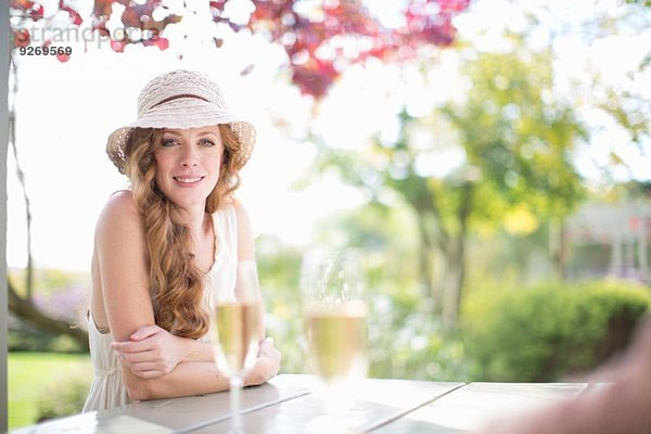 Portrait der schönen jungen Frau bei Tisch im Gartenrestaurant