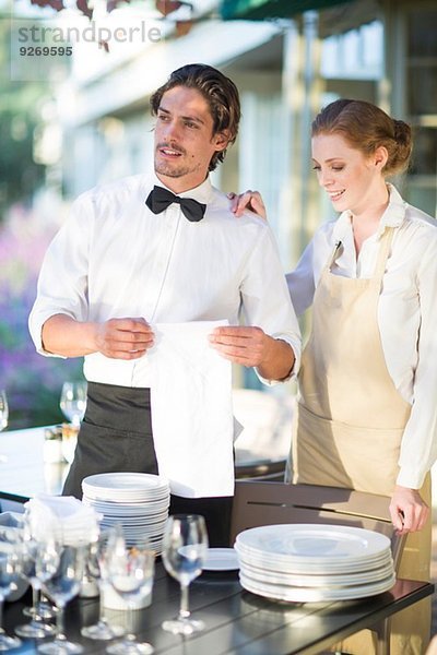 Kellnerin und Kellnerin beim Aufstellen der Tische im Terrassenrestaurant