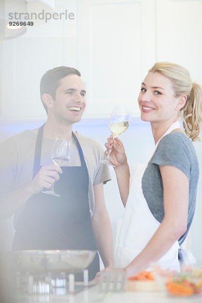 Paar beim Zubereiten von Speisen und Trinken von Weißwein in der Küche
