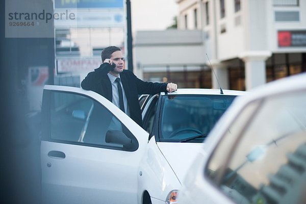 Mittlerer Erwachsener Geschäftsmann  der im Stau auf dem Smartphone chattet