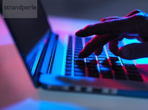 Silhouette der männlichen Hand Tippen auf Laptop-Tastatur bei Nacht