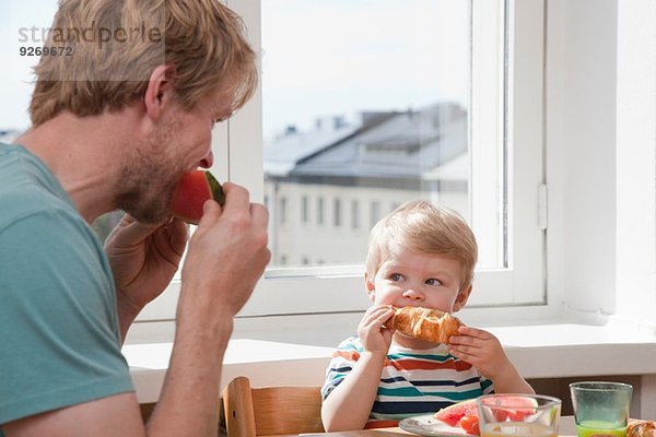 Vater und Kleinkind Sohn beim Frühstücken am Küchentisch