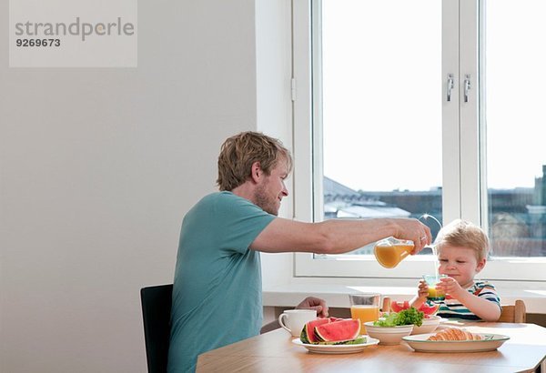 Vater und Kleinkind beim Frühstück am Küchentisch