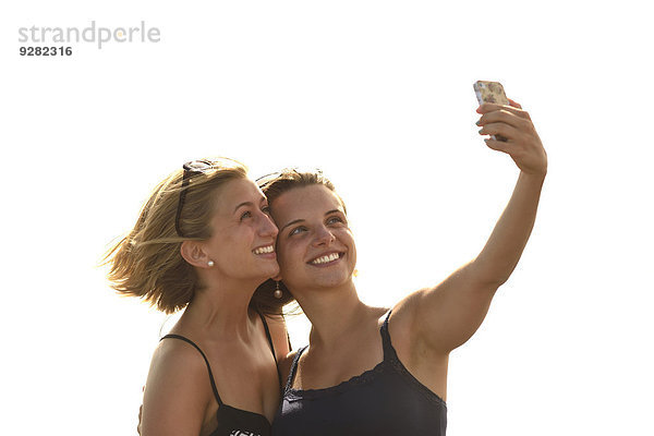 Selfie  zwei junge Frauen  machen Selbstportrait mit Handy  Lanzarote  Kanarische Inseln  Spanien
