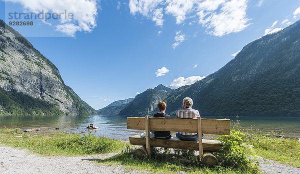 Zwei Personen sitzen auf Bank  blicken über den Königssee  St. Bartholomä am Königssee  Nationalpark Berchtesgaden  Berchtesgadener Land  Oberbayern  Bayern  Deutschland