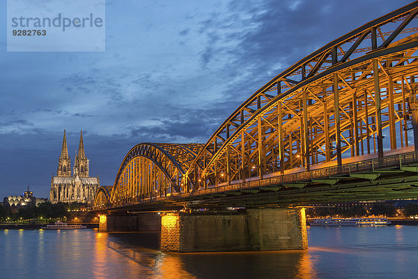 Kölner Dom mit Hohenzollernbrücke und Philharmonie in der Abenddämmerung  vorne Rhein  Köln  Nordrhein-Westfalen  Deutschland