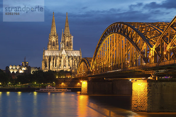 Kölner Dom mit Hohenzollernbrücke und Philharmonie in der Abenddämmerung  vorne Rhein  Köln  Nordrhein-Westfalen  Deutschland