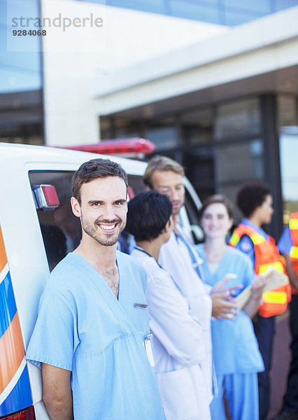 Krankenschwester lächelt mit dem Krankenwagen auf dem Krankenhausparkplatz