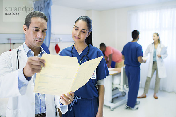 Arzt und Krankenschwester beim Lesen der Krankenakte im Krankenhauszimmer