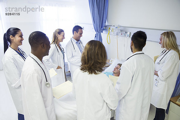 Arzt und Assistenzärzte untersuchen Patienten im Krankenhauszimmer