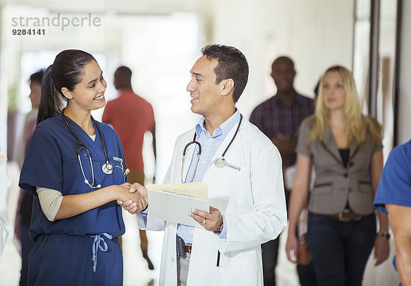 Arzt und Krankenschwester beim Händeschütteln im Krankenhausflur