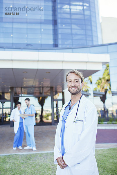 Arzt lächelt außerhalb des Krankenhauses