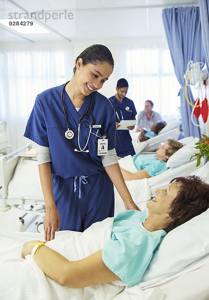 Krankenschwester im Gespräch mit Patientin im Krankenhauszimmer