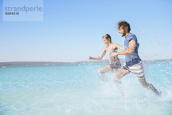 Paar  das am Strand im Wasser läuft