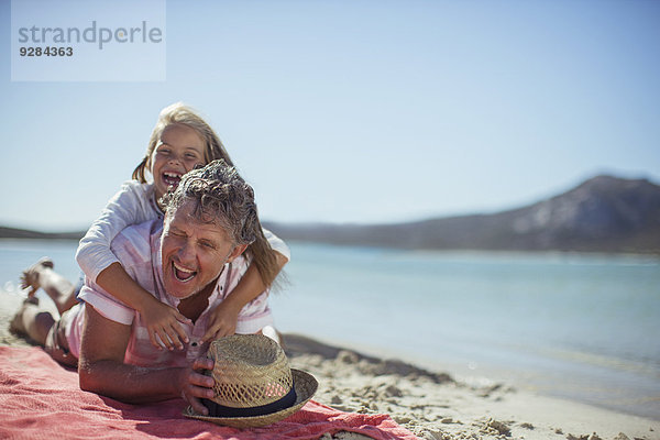 Großvater und Enkelin beim Spielen am Strand