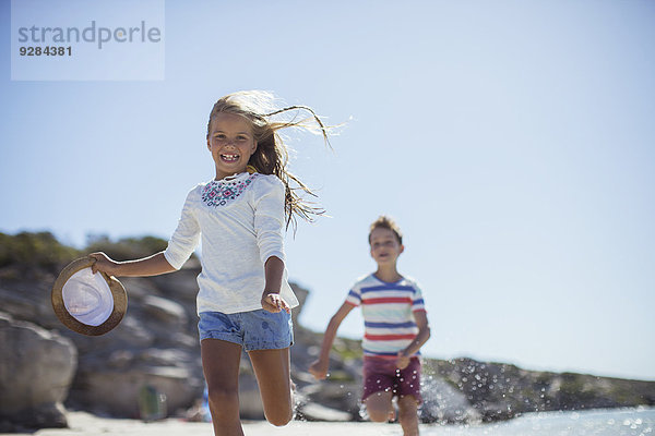 Junges Mädchen und Junge laufen am Strand entlang