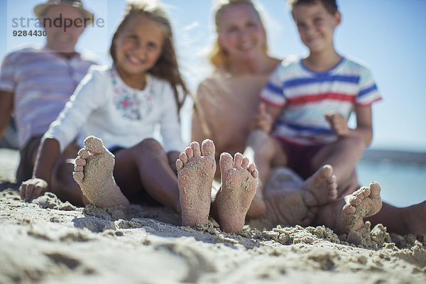 Familie sitzend mit Füßen im Sand