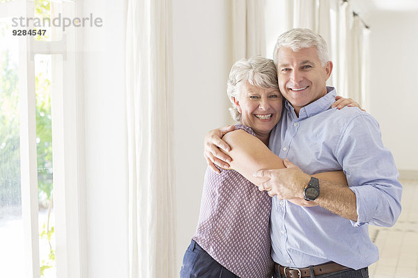 Ältere Paare umarmen sich im Wohnraum