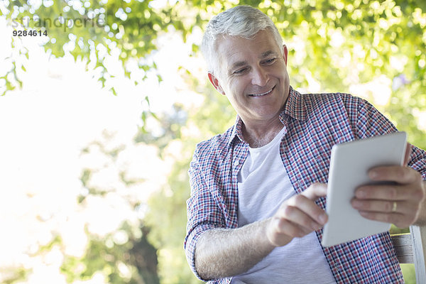 Älterer Mann mit digitalem Tablett im Freien