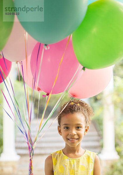 Junges Mädchen mit einem Haufen Luftballons