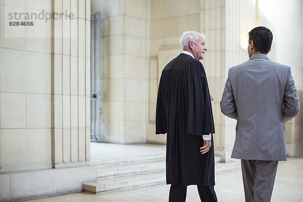 Richter und Anwalt gehen gemeinsam durchs Gerichtsgebäude.