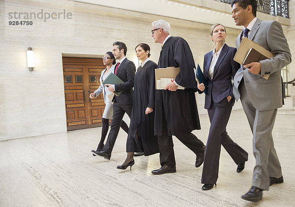 Richter und Anwälte gehen gemeinsam durchs Gerichtsgebäude.