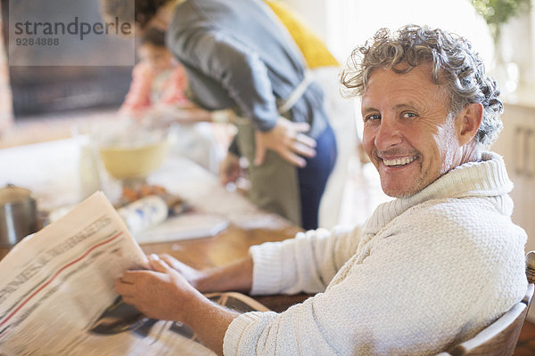 Älterer Mann liest Zeitung in der Küche