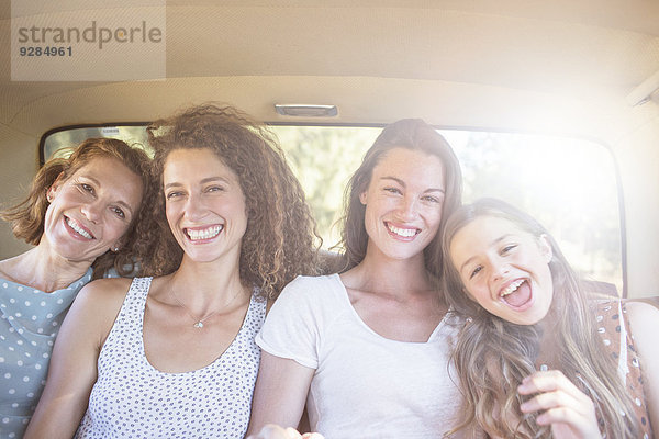 Vier Frauen sitzen auf dem Rücksitz des Autos.