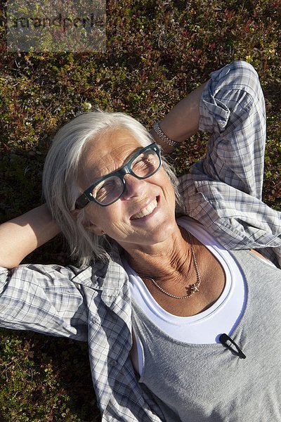 liegend liegen liegt liegendes liegender liegende daliegen Senior Senioren Frau lächeln Gras