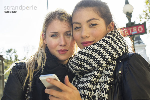 Junge Frauen im Freien schauen gemeinsam aufs Handy