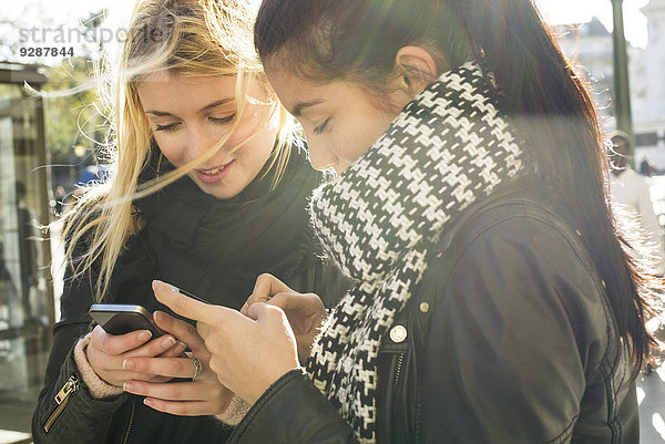 Junge Frauen schauen gemeinsam auf ihr individuelles Smartphone