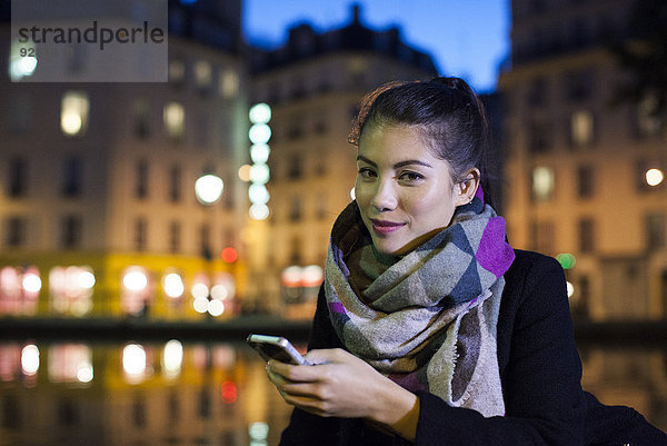 Junge Frau im Freien mit Smartphone  Portrait