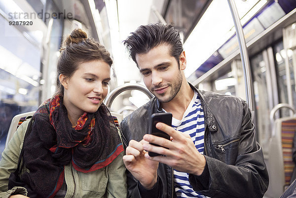 Freunde in der U-Bahn beim gemeinsamen Betrachten von Smartphones