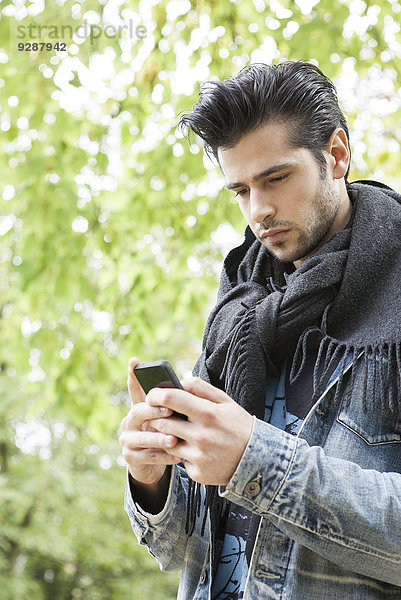 Junger Mann mit Smartphone im Freien