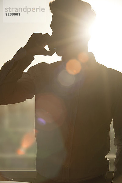 Mann spricht auf dem Handy  Silhouette von der Sonne durch das Fenster scheint