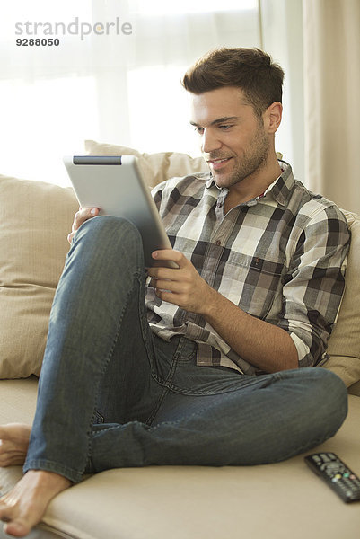 Junger Mann mit digitalem Tablett zu Hause