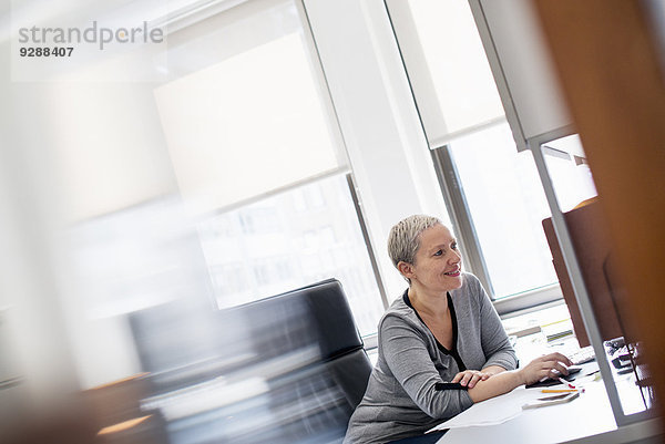 Eine Frau  die in einem Büro an einem Schreibtisch sitzt und eine Computermaus benutzt.